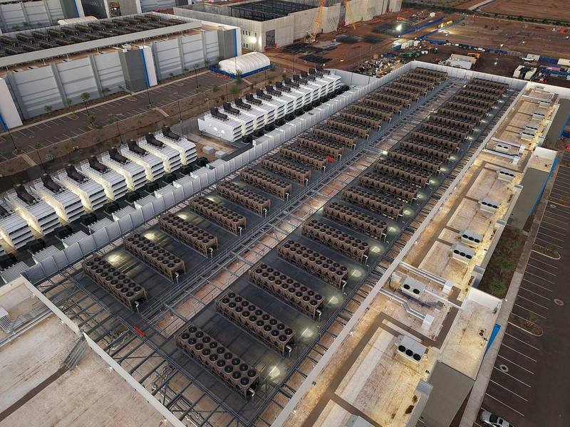Aerial view of a data center roof lined with cooling units at dusk
