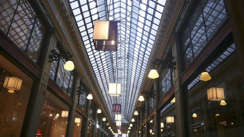 Glass-roofed shopping arcade lined with hanging lanterns and shopfronts