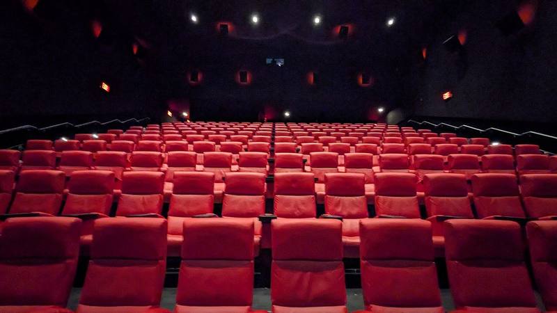 Rows of empty red seats in a darkened cinema auditorium