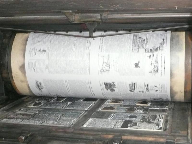 Newspaper page wrapped around the drum of a vintage printing press