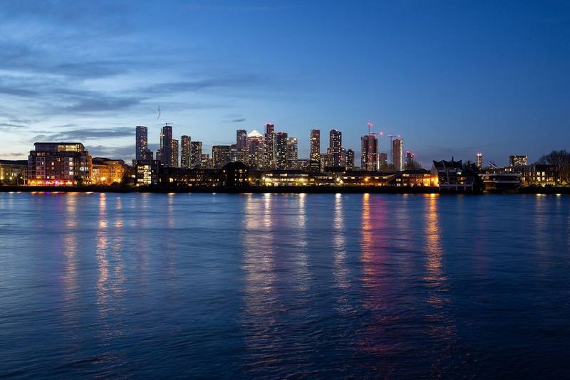 Business district skyline reflected in a river at blue hour